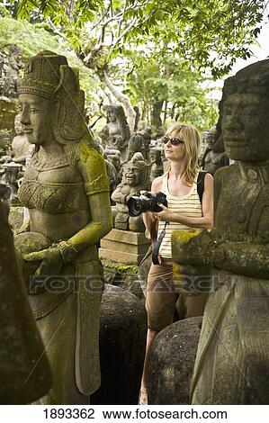 Stock Image - Tourist Looking At Statues For Sale. Fotosearch