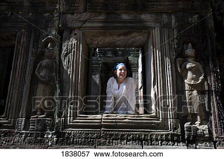 Stock Photo - Tourist Looking Trough Temple Window In Ancient City Of Angkor; Angkor Wat, Siem Reap, Cambodia. Fotosearch