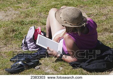 Stock Image - Tourist relaxing and reading a book on her tablet above Chamonix-Mont Blanc valley; France. Fotosearch