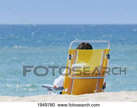 Stock Image - Tourist Relaxing On A Chair On The Beach On Cala De Mijas; Fuengirola Malaga Province Costa Del Sol Spain. Fotosearch