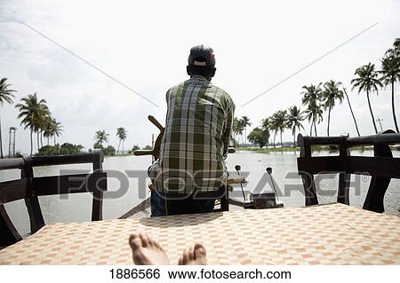 Tourist Riding On A House Boat While Local Steers View Large Photo Image Stock Photograph - Tourist Riding On A House Boat While Local Steers. Fotosearch