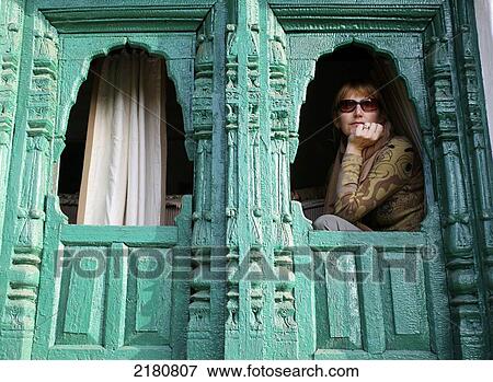 Tourist sits in a window with a turquoise wall while trekking in the Himalayas; India View Large Photo Image Stock Photo - Tourist sits in a window with a turquoise wall while trekking in the Himalayas; India. Fotosearch