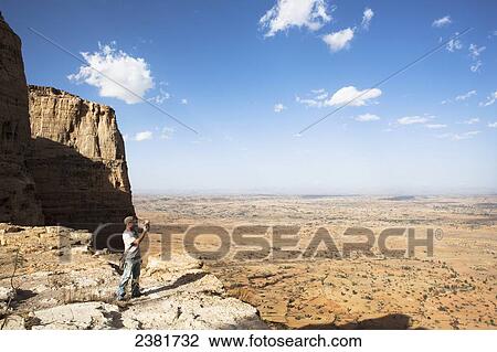 Stock Image - Tourist trekking in the amazing mountain scenery on the Gheralta plateau; Tigray region, Ethiopia. Fotosearch