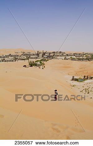 Stock Photo - Tourist walking in the Empty Quarter in Liwa Oasis; Liwa Oasis, Abu Dhabi, United Arab Emirates. Fotosearch
