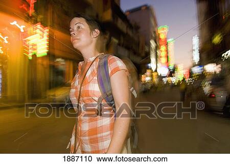 Stock Image - Tourist With Backpack Walking Down Small Street In Delhi At Dusk, Blurred Motion. Fotosearch