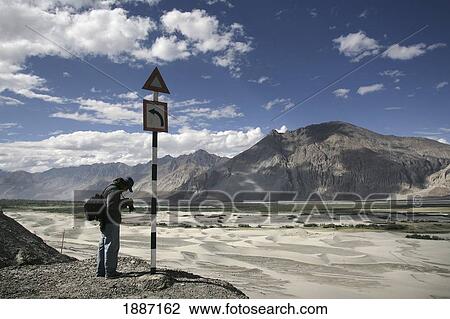 Stock Image - Tourist With Camera On High Altitude Desert At Hundar. Fotosearch