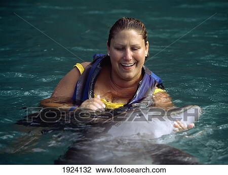 Stock Image - Tourist With Dolphin At Dolphin Cove. Fotosearch