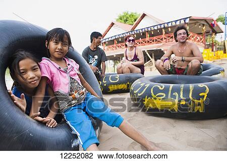Tourists and children pose with inner tubes on the beach on the island of Don Det; Si Phan Don, Laos View Large Photo Image Stock Image - Tourists and children pose with inner tubes on the beach on the island of Don Det; Si Phan Don, Laos. Fotosearch