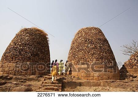Stock Image - Tourists at domed stone structures; Badami, Karnatak, India. Fotosearch