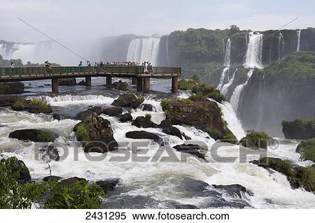 Stock Photography - Tourists crowd on to concrete walkways above the waterfalls at Iguacu National Park; Brazil. Fotosearch