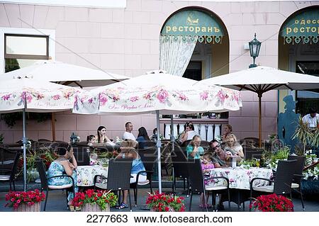 Stock Image - Tourists dining in street cafes outside historic buildings in Odessa city centre; Odessa, Ukraine. Fotosearch