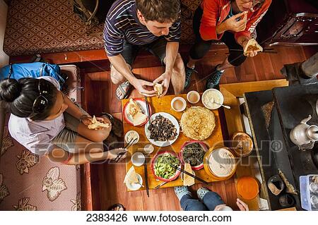 Stock Photograph - Tourists eating authentic tibetan lunch; Zhongdian, Yunnan, China. Fotosearch
