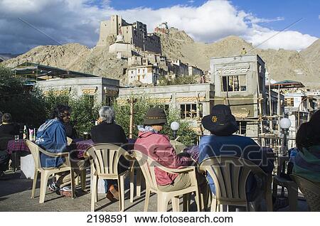 Stock Image - Tourists enjoying a drink below the Leh Palace. Leh was the capital of the Himalayan kingdom of Ladakh, now the Leh District in the state of Jammu and Kashmir, India. Leh is at an altitude of 3, 500 meters (11, 483 ft).. Fotosearch