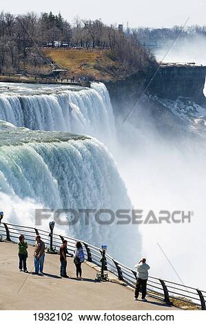 Stock Image - Tourists Enjoying The View Of Niagara Falls, Ontario And New York Border, Canada And United States Of America. Fotosearch