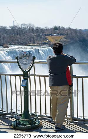 Stock Image - Tourists Enjoying The View Of Niagara Falls, Ontario And New York Border, Canada And United States Of America. Fotosearch
