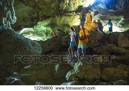 Stock Image - Tourists exploring in a cave; Niue. Fotosearch