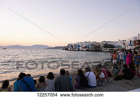 Tourists gathered along the seafront in the Little Venice area of Mykonos Town to watch the sunset; Mykonos, Cyclades, Greek Islands, Greece View Large Photo Image Picture - Tourists gathered along the seafront in the Little Venice area of Mykonos Town to watch the sunset; Mykonos, Cyclades, Greek Islands, Greece. Fotosearch