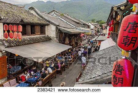 Stock Image - Tourists in cafes along the street; Dali, Yunnan, China. Fotosearch