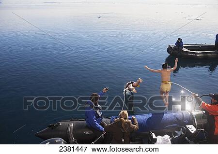 Tourists jump off a boat into the freezing waters of the Arctic Ocean; Svalbard, Norway View Large Photo Image Stock Photo - Tourists jump off a boat into the freezing waters of the Arctic Ocean; Svalbard, Norway. Fotosearch