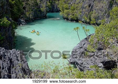 Tourists Kayak Inside The Scenic Small Lagoon On Miniloc Island, Near El Nido; Bacuit Archipelago, Palawan, Philippines View Large Photo Image Stock Photo - Tourists Kayak Inside The Scenic Small Lagoon On Miniloc Island, Near El Nido; Bacuit Archipelago, Palawan, Philippines. Fotosearch