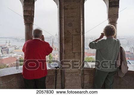 Stock Image - Tourists Looking At Pest From The Halaszbastya Or Fisherman's Bastion, Budapest, Hungary. Fotosearch