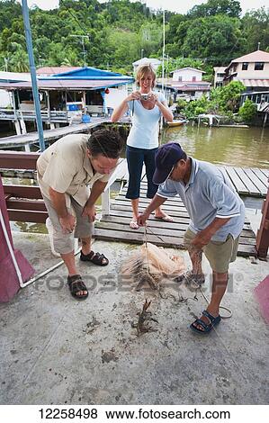 Stock Photo - Tourists practicing their net fishing at a small village; Brunei. Fotosearch