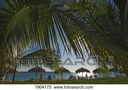 Stock Image - Tourists Relaxing At Ancon Beach (Playa Ancon) At Sunset, Trinidad, Cuba. Fotosearch