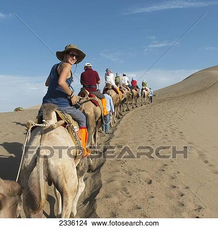 Picture - Tourists Ride In A Row On Camels; Jiuquan, Gansu, China. Fotosearch
