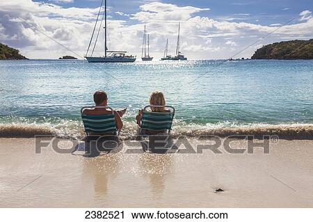 Tourists sit at the water's edge on a beach in the Virgin Islands; United States of America View Large Photo Image Stock Image - Tourists sit at the water's edge on a beach in the Virgin Islands; United States of America. Fotosearch