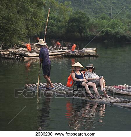 Stock Photo - Tourists Sit On A Boat Being Rowed Down Yulong River; Guilin, Guangxi, China. Fotosearch