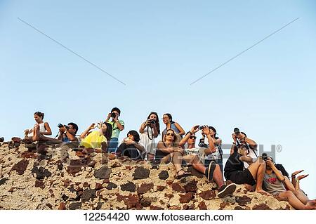 Tourists sit on a rugged ledge with cameras; Oia, Santorini, Greece View Large Photo Image Stock Image - Tourists sit on a rugged ledge with cameras; Oia, Santorini, Greece. Fotosearch