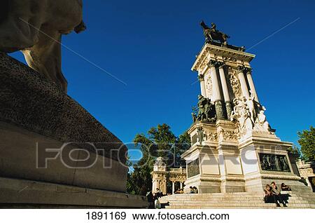 Stock Photo - Tourists Sitting Under Alfonso Xii Monument At Paeque Del Retiro. Fotosearch