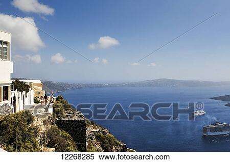 Stock Photography - Tourists stroll along the walkway above the sea; Imerovigli, Santorini, Greece. Fotosearch