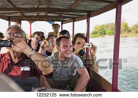 Stock Photography - Tourists take a ferry on the Mekong River to the Island of Don Det; Laos. Fotosearch