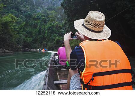 Stock Photo - Tourists taking a longboat tour of stunning caves, 7 kilometre caves; Kong Lor, Laos. Fotosearch