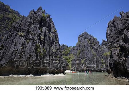 Stock Photo - Tourists Wade In The Small Lagoon On Miniloc Island, Near El Nido; Bacuit Archipelago, Palawan, Philippines. Fotosearch