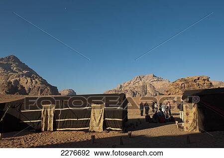 Stock Image - Tourists waiting to be picked up after spending the night in a Bedouin camp in the middle of the Wadi Rum desert; Jordan. Fotosearch