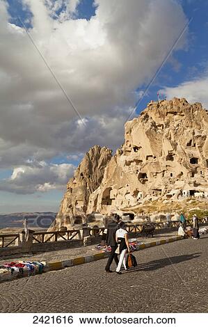 Stock Photograph - Tourists walk on the road towards Uchisar Castle; Uchisar, Cappadocia, Turkey. Fotosearch