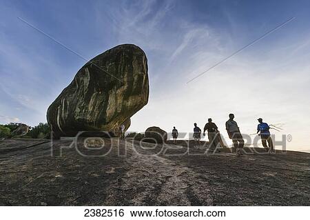 Stock Photograph - Tourists walking by Kopjes, musical rock, Serengeti National Park; Tanzania. Fotosearch