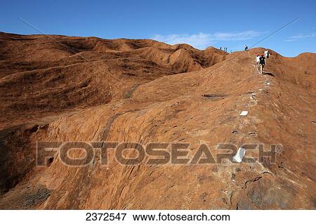 Stock Photo - Tourists walking up Uluru, formerly known as Ayers Rock; Northern Territory, Australia. Fotosearch