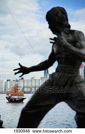 Traditional Chinese Junk Boat In Background. Bruce Lee Memorial Statue, View Of Victoria Harbour, Hong Kong Island Skyline, From Tsim Sha Tsui, Kowloon; Tsim Sha Tsui, Kowloon, Hong Kong, China View Large Photo Image Stock Photograph - Traditional Chinese Junk Boat In Background. Bruce Lee Memorial Statue, View Of Victoria Harbour, Hong Kong Island Skyline, From Tsim Sha Tsui, Kowloon; Tsim Sha Tsui, Kowloon, Hong Kong, China. Fotosearch