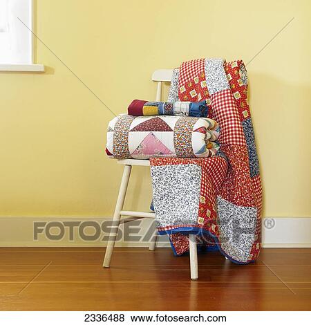 Traditional Quilts Stacked On A Chair In A Yellow Room; Victoria, Vancouver Island, British Columbia, Canada View Large Photo Image Stock Photo - Traditional Quilts Stacked On A Chair In A Yellow Room; Victoria, Vancouver Island, British Columbia, Canada. Fotosearch