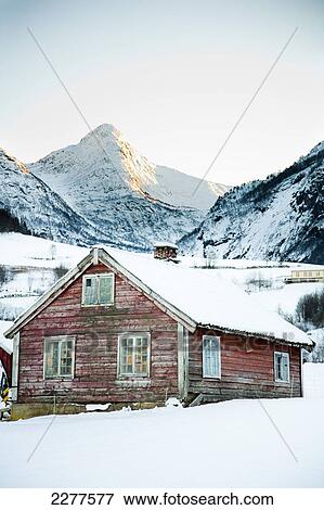 Stock Photo - Traditional red wooden building in the village with sun setting over the mountains in the winter with snow; Ortnevik, Sognefjord, Norway. Fotosearch