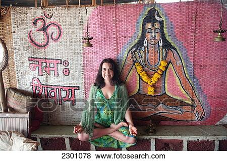 Trained yoga teacher doing yoga pose/ posture with hand mudras in front of Shiva Hindu god wall painting at Shore Bar/ cafe/ restaurant along Anjuna Beach. Goa State, India, Asia. View Large Photo Image Stock Photo - Trained yoga teacher doing yoga pose/ posture with hand mudras in front of Shiva Hindu god wall painting at Shore Bar/ cafe/ restaurant along Anjuna Beach. Goa State, India, Asia.. Fotosearch