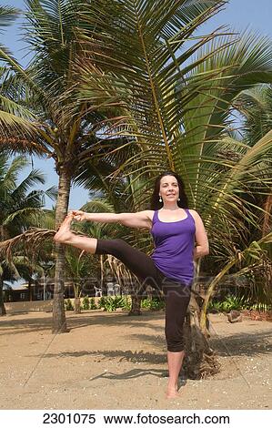 Stock Photography - Trained yoga teacher doing yoga poses/ postures along Anjuna Beach. Goa State, India, Asia.. Fotosearch