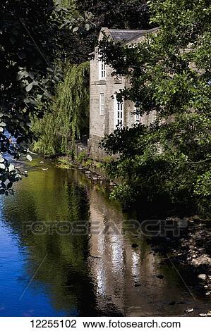 Stock Image - Tranquil canal with reflection of a building and trees; Yorkshire, England. Fotosearch
