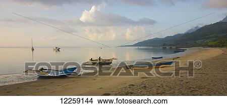 Tranquil ocean at sunrise with boats on the beach; Atauro Island, Timor-Leste View Large Photo Image Picture - Tranquil ocean at sunrise with boats on the beach; Atauro Island, Timor-Leste. Fotosearch