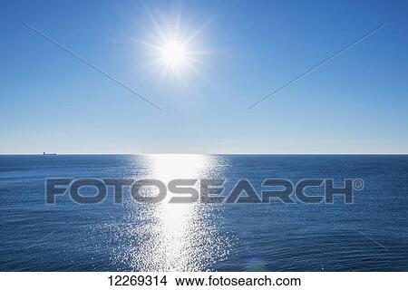 Picture - Tranquil ocean water reflecting sunlight with sun in the blue sky; Genoa, Liguria, Italy. Fotosearch