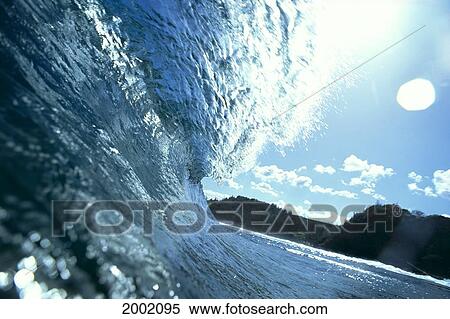 Stock Photography - Translucent Curling Blue Wave Backlit, Shimmery Waters, Land In Background. Fotosearch