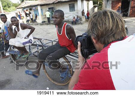 Traveling Surfer, Writer And Photographer Taking Photo Of Men In Street, Tanzania View Large Photo Image Stock Image - Traveling Surfer, Writer And Photographer Taking Photo Of Men In Street, Tanzania. Fotosearch